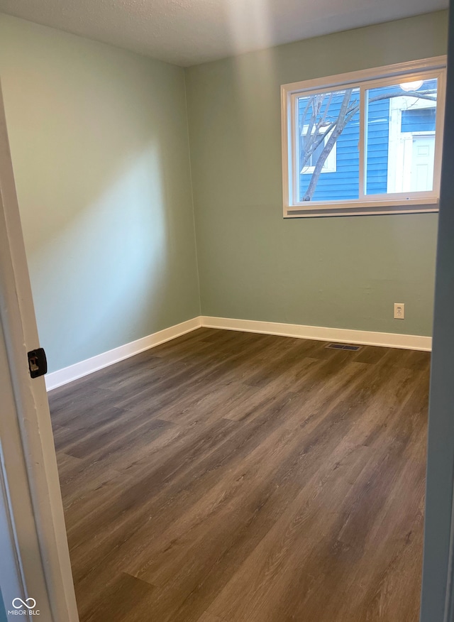 spare room with a textured ceiling and dark hardwood / wood-style floors