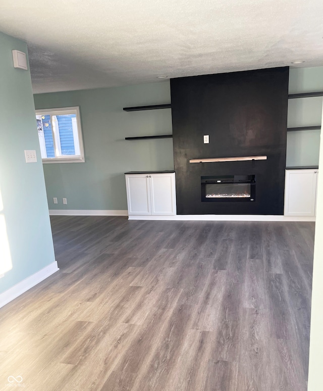 unfurnished living room featuring wood-type flooring and a textured ceiling