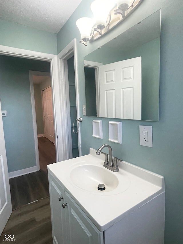 bathroom featuring wood-type flooring, vanity, and a textured ceiling