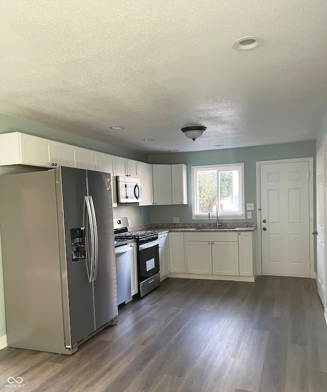 kitchen featuring white cabinetry, sink, appliances with stainless steel finishes, a textured ceiling, and dark hardwood / wood-style flooring