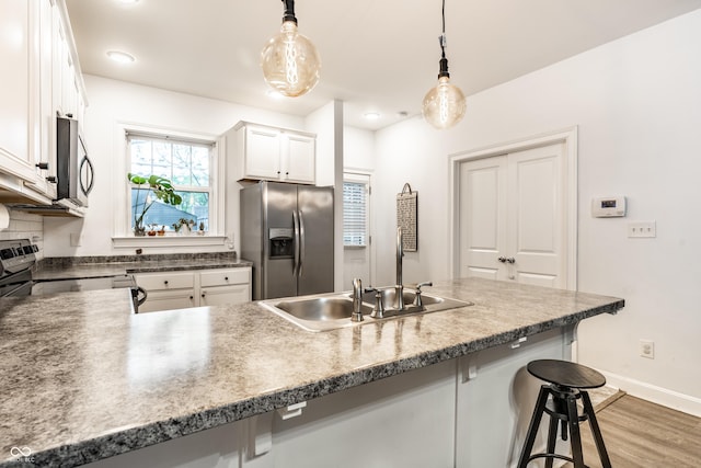 kitchen featuring hanging light fixtures, a breakfast bar area, white cabinets, baseboards, and appliances with stainless steel finishes