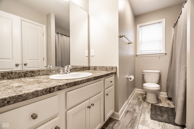 bathroom with vanity, toilet, and baseboards