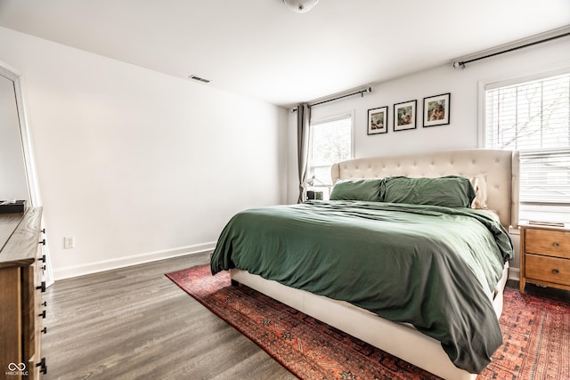 bedroom featuring baseboards, visible vents, and wood finished floors