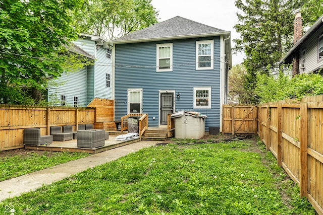 rear view of property featuring a lawn, outdoor lounge area, a shingled roof, a deck, and a fenced backyard