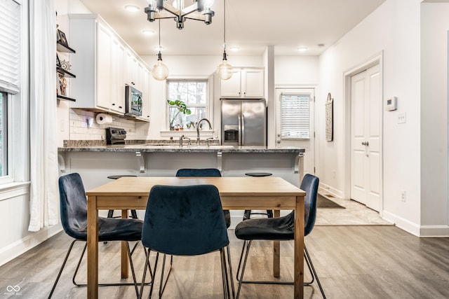 kitchen featuring baseboards, hanging light fixtures, a peninsula, stainless steel appliances, and white cabinets