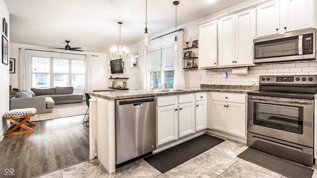 kitchen featuring backsplash, a wealth of natural light, a peninsula, and appliances with stainless steel finishes