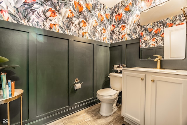bathroom featuring vanity, toilet, and wallpapered walls