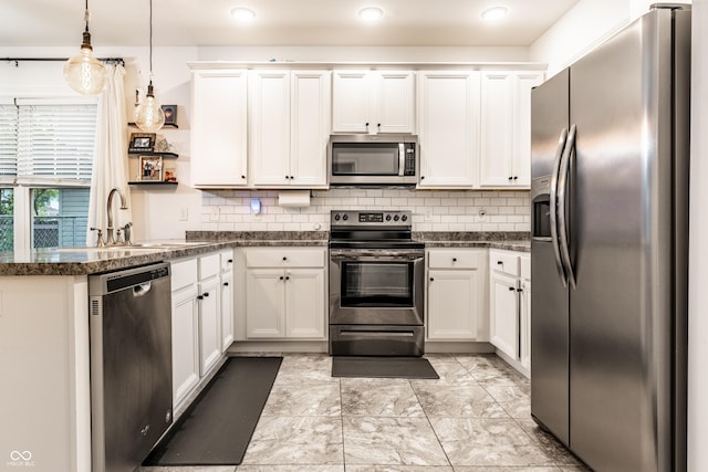 kitchen with a peninsula, backsplash, appliances with stainless steel finishes, and a sink