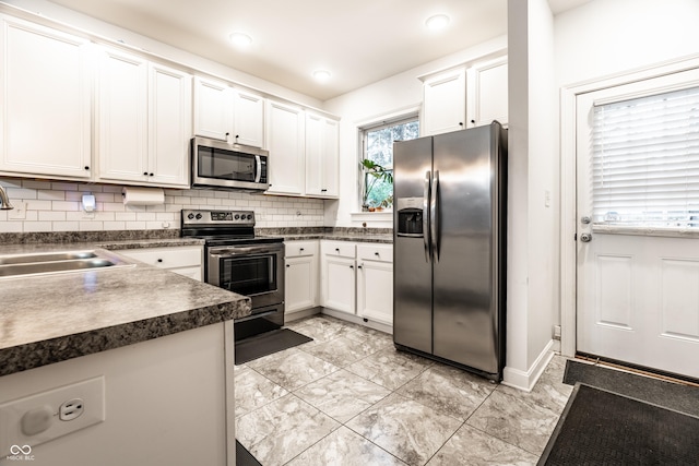 kitchen with a sink, stainless steel appliances, decorative backsplash, white cabinets, and dark countertops