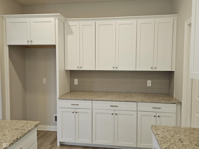 kitchen featuring backsplash, white cabinets, and light stone countertops