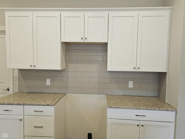 kitchen with white cabinets, light stone countertops, and decorative backsplash