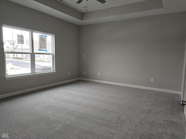 carpeted spare room featuring ceiling fan and a tray ceiling