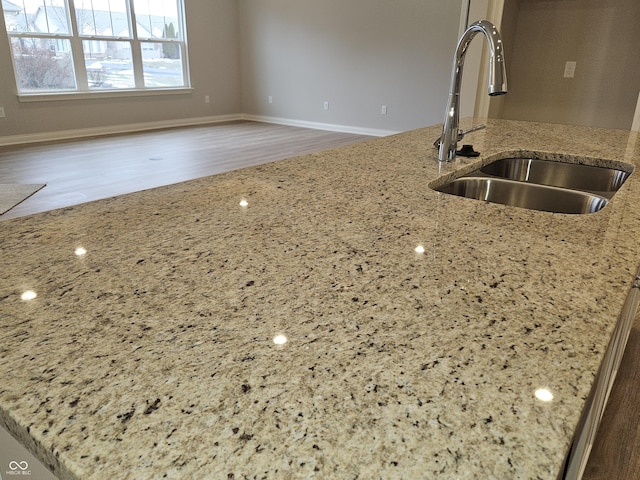 kitchen featuring light stone counters, sink, and hardwood / wood-style floors