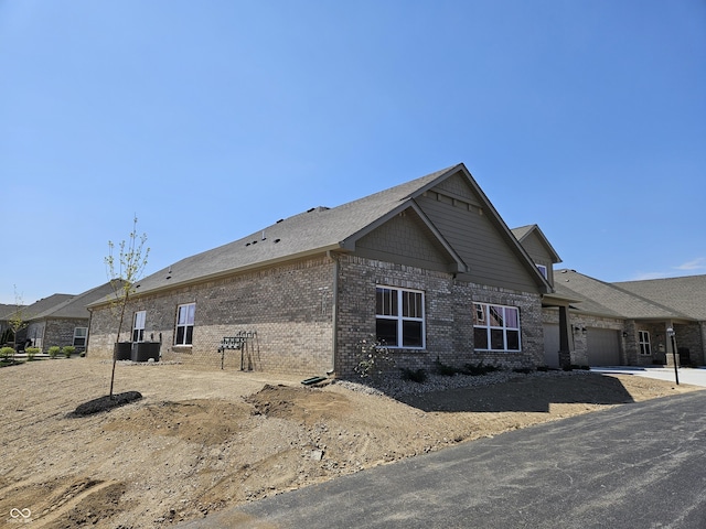 view of property exterior with central AC, an attached garage, and brick siding