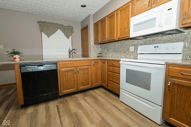 kitchen with a textured ceiling, sink, light hardwood / wood-style floors, and white appliances