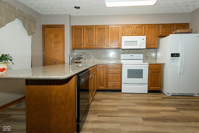 kitchen with sink, white appliances, kitchen peninsula, and light wood-type flooring