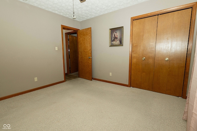 unfurnished bedroom featuring ceiling fan, light colored carpet, a textured ceiling, and a closet