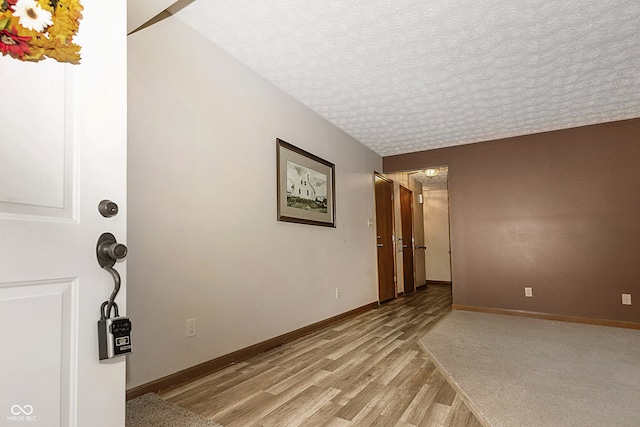 empty room with light hardwood / wood-style floors and a textured ceiling