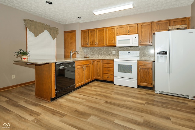 kitchen featuring kitchen peninsula, a textured ceiling, white appliances, and light hardwood / wood-style flooring