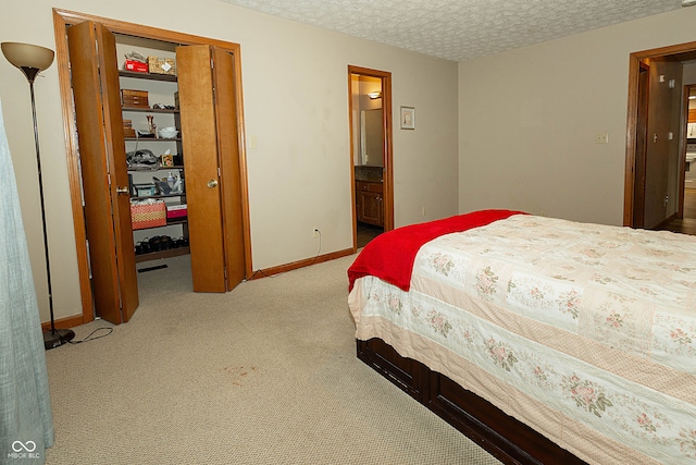 carpeted bedroom featuring connected bathroom, a closet, and a textured ceiling