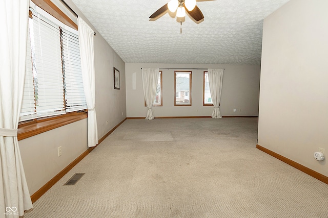 spare room featuring a textured ceiling, ceiling fan, and light carpet