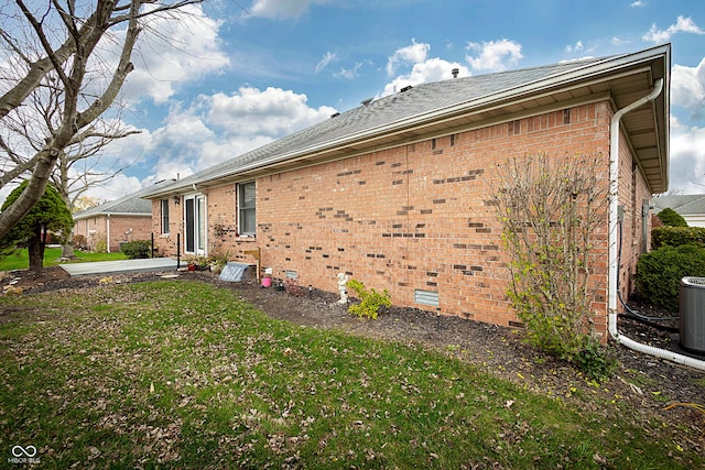 view of side of property featuring cooling unit, a patio area, and a yard