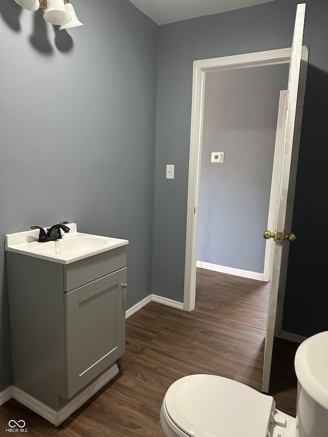 bathroom with wood-type flooring, toilet, and vanity