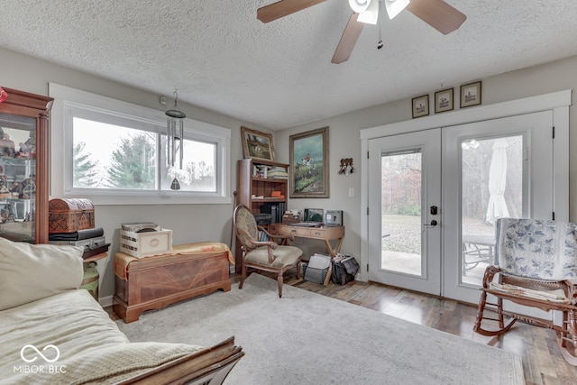 living room with ceiling fan, a textured ceiling, light hardwood / wood-style flooring, and french doors