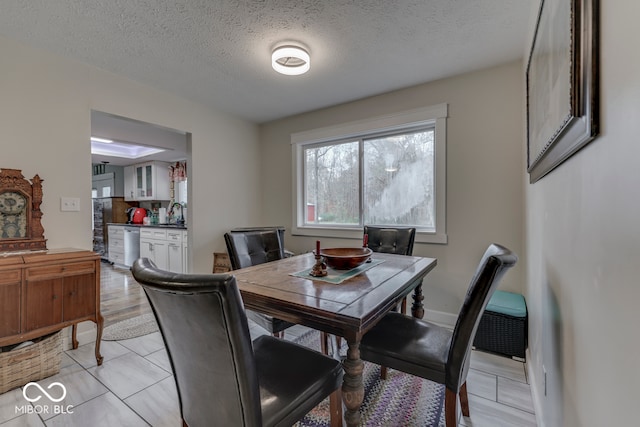 dining area featuring light wood-type flooring and a textured ceiling