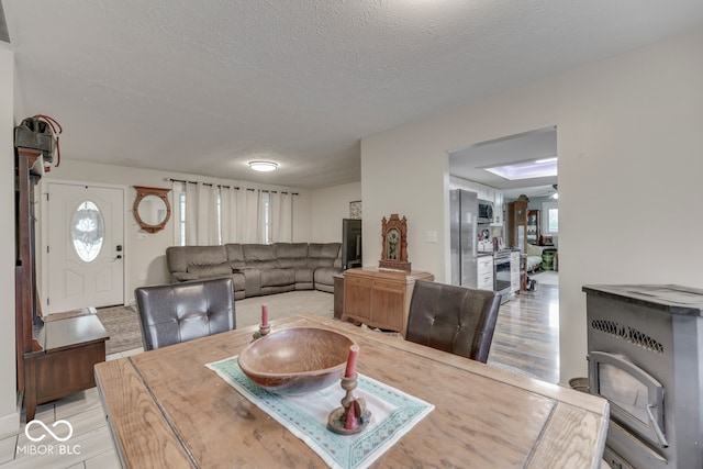 dining area with light wood-type flooring, a textured ceiling, and ceiling fan