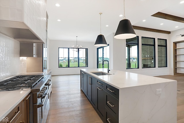 kitchen featuring sink, backsplash, hanging light fixtures, range with two ovens, and a spacious island