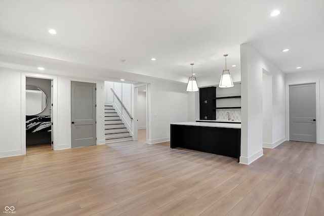 kitchen with a kitchen island, hanging light fixtures, decorative backsplash, and light hardwood / wood-style flooring