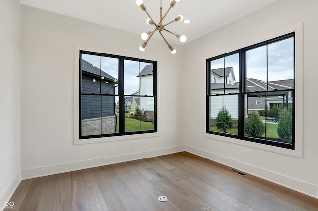 unfurnished room featuring light hardwood / wood-style flooring and a notable chandelier