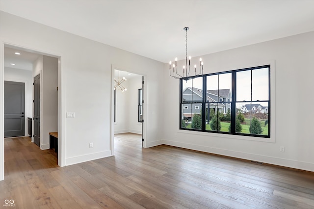 unfurnished dining area featuring light hardwood / wood-style floors and a chandelier