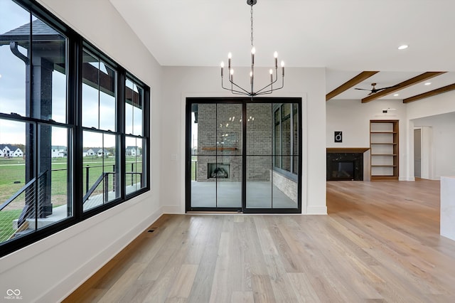 unfurnished dining area featuring beamed ceiling, plenty of natural light, and light wood-type flooring