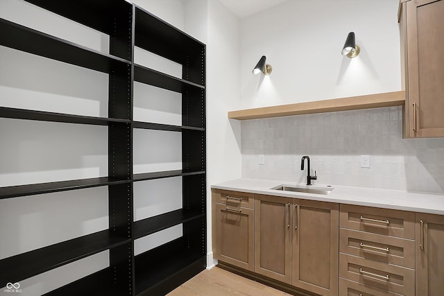 interior space featuring light wood-type flooring, sink, and tasteful backsplash