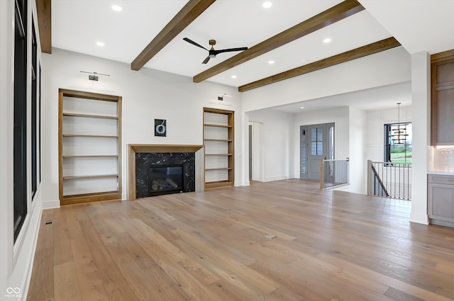 unfurnished living room with light wood-type flooring, a premium fireplace, and beam ceiling