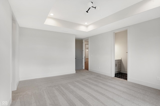 carpeted empty room with a raised ceiling