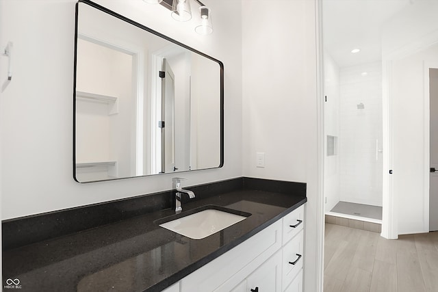 bathroom featuring vanity, hardwood / wood-style floors, and a tile shower