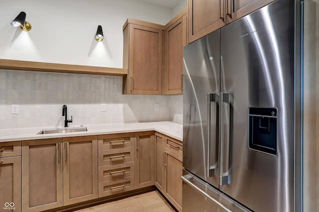 kitchen with light hardwood / wood-style floors, stainless steel fridge, sink, and decorative backsplash