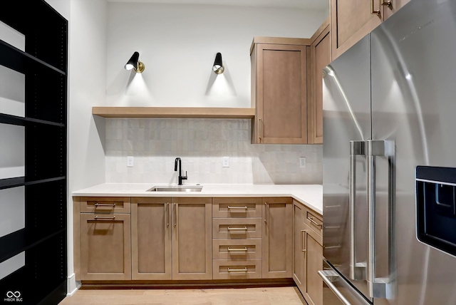 kitchen with stainless steel fridge, sink, backsplash, and light hardwood / wood-style flooring