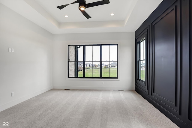 carpeted spare room featuring ceiling fan and a raised ceiling