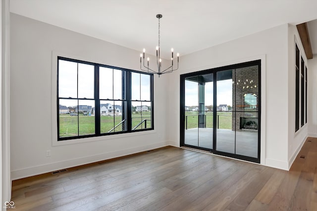 unfurnished room with hardwood / wood-style flooring and an inviting chandelier