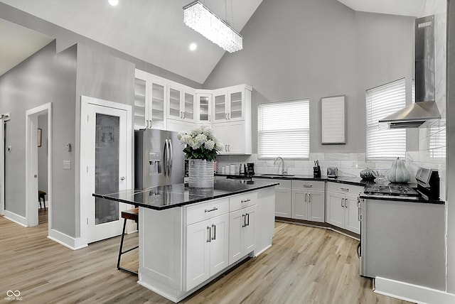 kitchen featuring appliances with stainless steel finishes, exhaust hood, high vaulted ceiling, white cabinets, and a center island