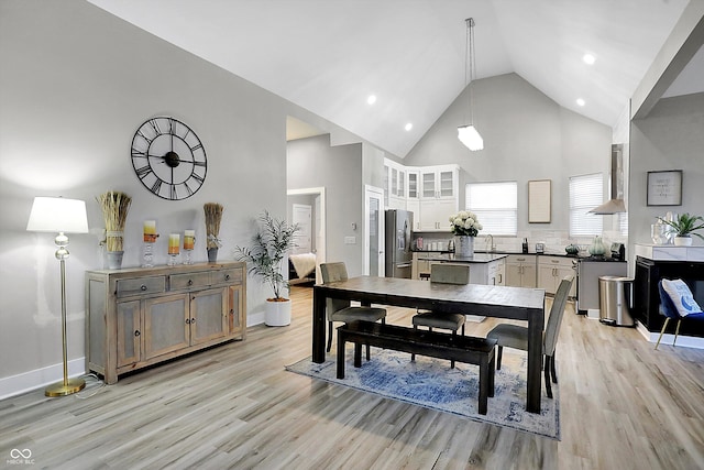 dining space featuring light hardwood / wood-style floors, high vaulted ceiling, ceiling fan, and sink