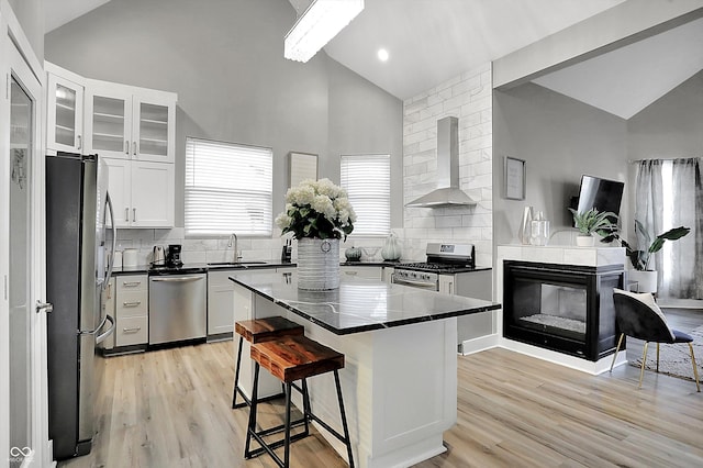 kitchen with white cabinetry, wall chimney range hood, a center island, and appliances with stainless steel finishes