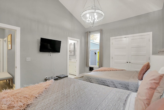 bedroom featuring a closet, ensuite bath, a notable chandelier, and lofted ceiling