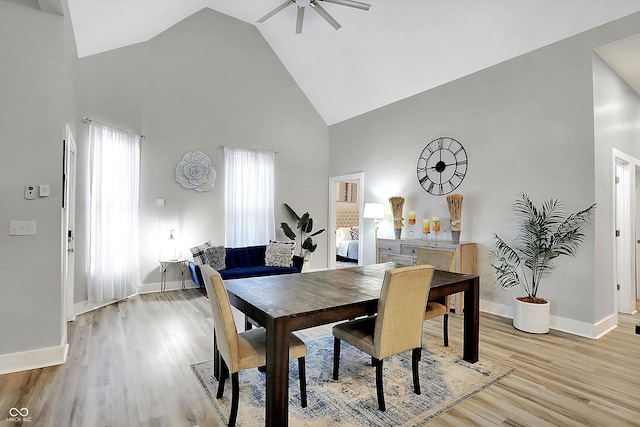 dining area with light hardwood / wood-style flooring, high vaulted ceiling, and ceiling fan