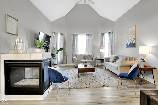 living room featuring a tile fireplace, hardwood / wood-style floors, and high vaulted ceiling