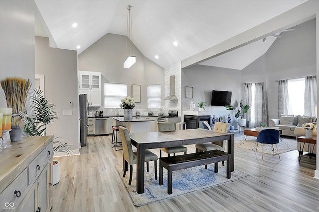 dining room with light wood-type flooring, high vaulted ceiling, and plenty of natural light